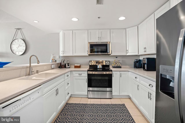 kitchen featuring sink, white cabinets, stainless steel appliances, and light tile patterned floors