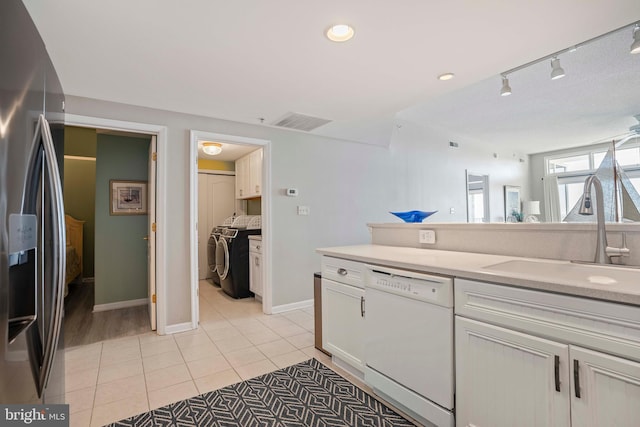 bathroom featuring tile patterned flooring, washer / dryer, rail lighting, and sink