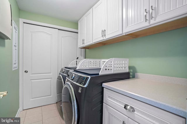 clothes washing area with light tile patterned flooring, cabinets, and independent washer and dryer