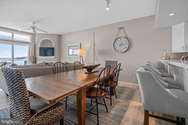 dining space featuring a textured ceiling, light wood-type flooring, and ceiling fan