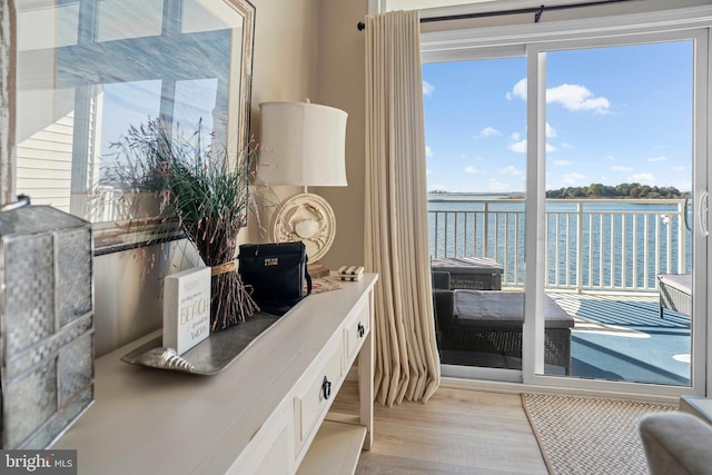 doorway to outside with a water view and light hardwood / wood-style flooring