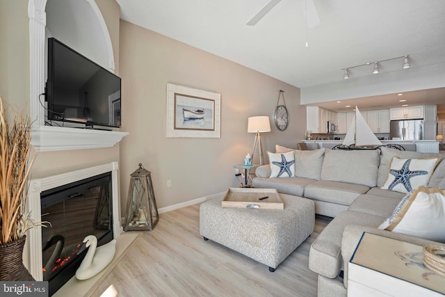 living room featuring ceiling fan, rail lighting, and light hardwood / wood-style flooring