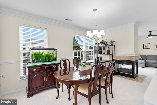 dining space with light carpet, ornamental molding, ceiling fan with notable chandelier, and a healthy amount of sunlight