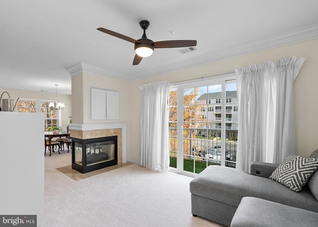 sitting room with ceiling fan with notable chandelier, ornamental molding, light colored carpet, and a multi sided fireplace