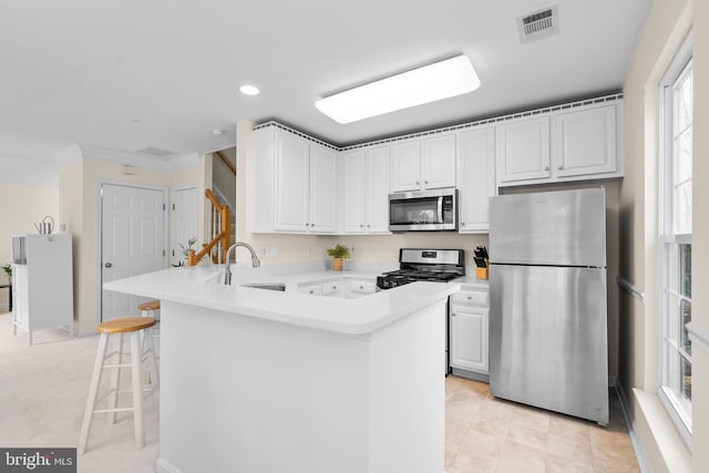 kitchen featuring kitchen peninsula, a breakfast bar, stainless steel appliances, sink, and white cabinets