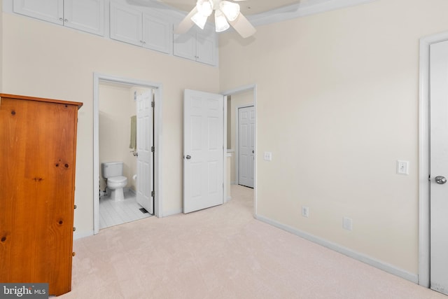 unfurnished bedroom featuring ceiling fan, a towering ceiling, light carpet, and connected bathroom