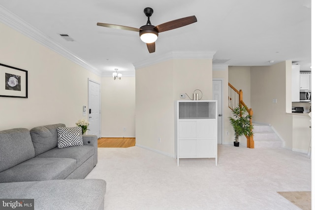 carpeted living room with ceiling fan and ornamental molding