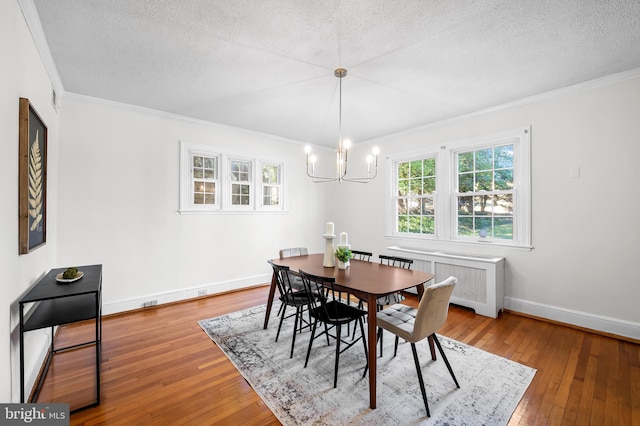 dining room featuring radiator, baseboards, ornamental molding, hardwood / wood-style flooring, and a textured ceiling