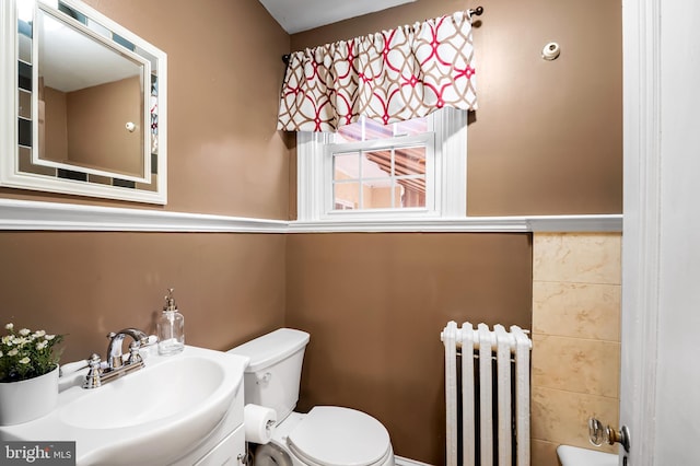 bathroom featuring toilet, vanity, radiator heating unit, and a bathtub