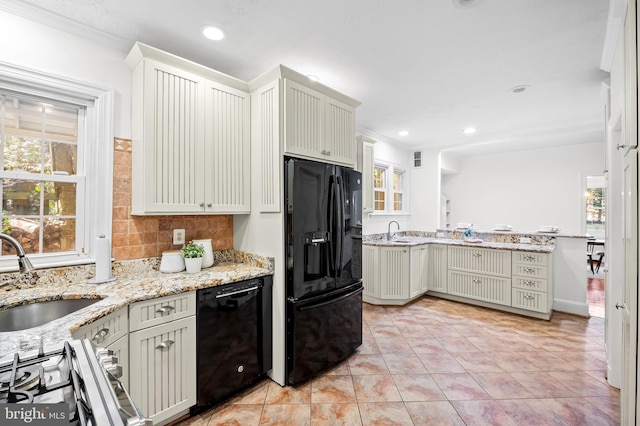 kitchen featuring a sink, decorative backsplash, light stone counters, and black appliances