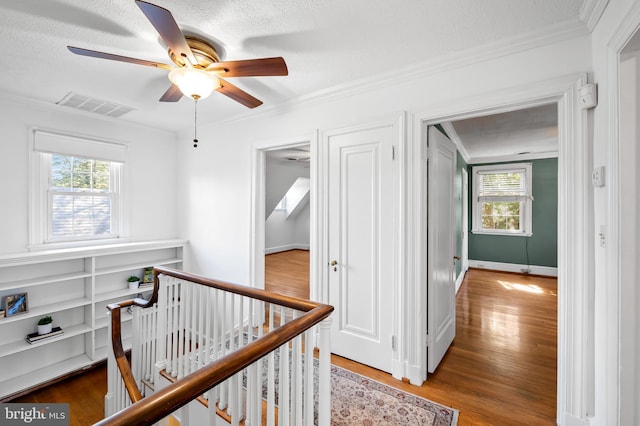 corridor with visible vents, an upstairs landing, plenty of natural light, and crown molding