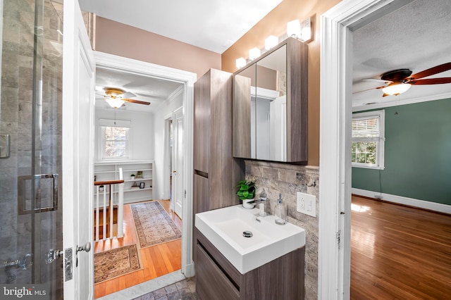 bathroom with plenty of natural light, wood finished floors, baseboards, and decorative backsplash