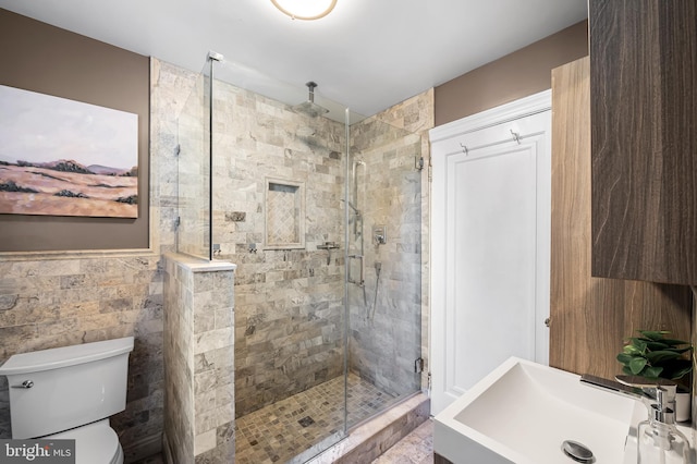 full bath featuring a sink, toilet, tile walls, and a stall shower