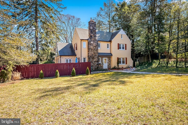 rear view of property with a chimney, stucco siding, a lawn, and fence