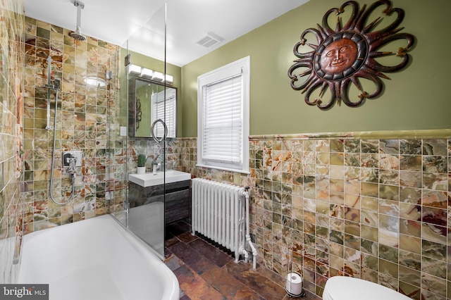 bathroom featuring visible vents, radiator, walk in shower, wainscoting, and tile walls