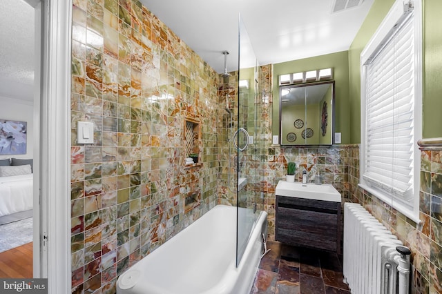 bathroom featuring visible vents, tile walls, radiator heating unit, a combined bath / shower with rainfall shower, and vanity