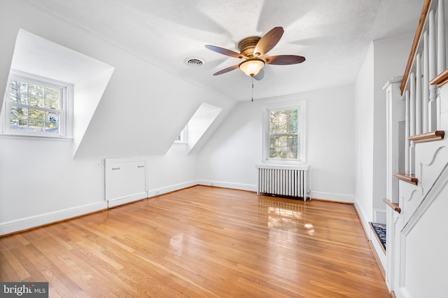 bonus room with light wood-style floors, visible vents, radiator, and a wealth of natural light