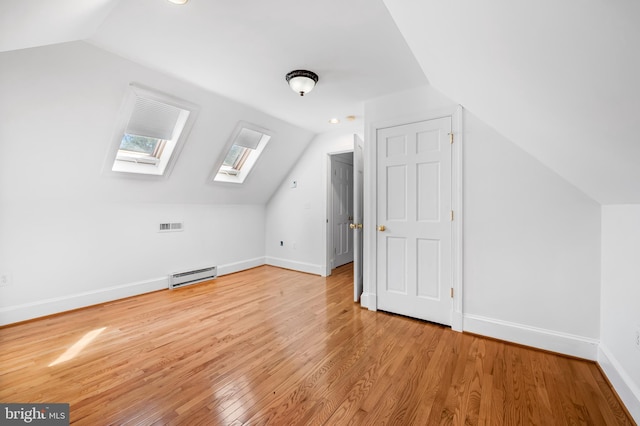 bonus room with visible vents, baseboards, lofted ceiling with skylight, baseboard heating, and light wood-style flooring