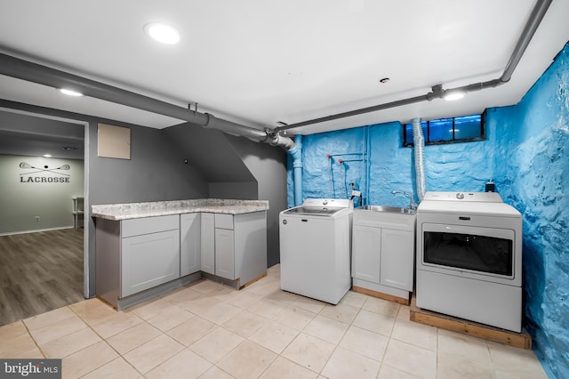 laundry area with a sink, cabinet space, light tile patterned floors, and washing machine and clothes dryer