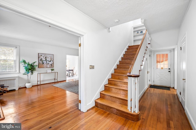 staircase featuring baseboards, wood-type flooring, a textured ceiling, and radiator