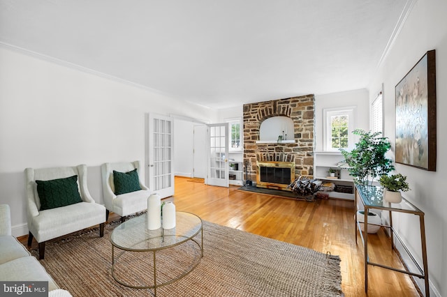 living area featuring french doors, a healthy amount of sunlight, a fireplace, and hardwood / wood-style flooring