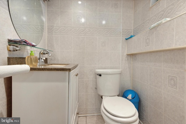 bathroom with tile patterned flooring, vanity, tile walls, and toilet