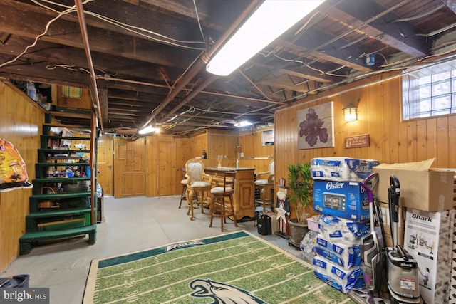 basement featuring bar area and wood walls