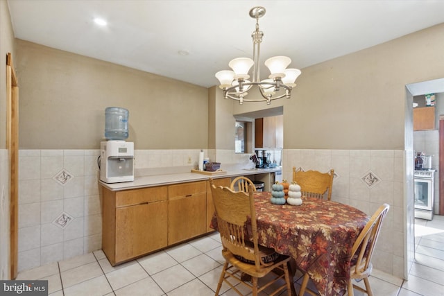 dining room with a chandelier, light tile patterned floors, and tile walls