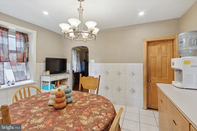 dining room with a notable chandelier, light tile patterned flooring, and tile walls