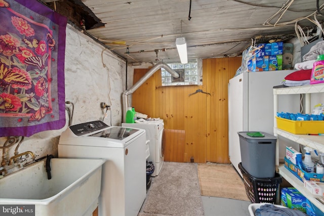 laundry room featuring washing machine and clothes dryer, wooden walls, and sink