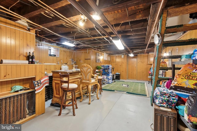 basement featuring wooden walls and indoor bar