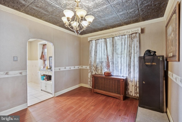 interior space featuring crown molding, wood-type flooring, and a notable chandelier