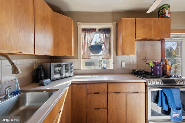 kitchen featuring decorative backsplash, stainless steel stove, plenty of natural light, and sink