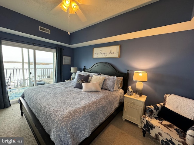 carpeted bedroom featuring access to outside, a water view, and ceiling fan