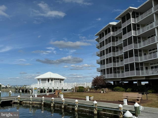 view of property's community with a water view, a dock, and a yard