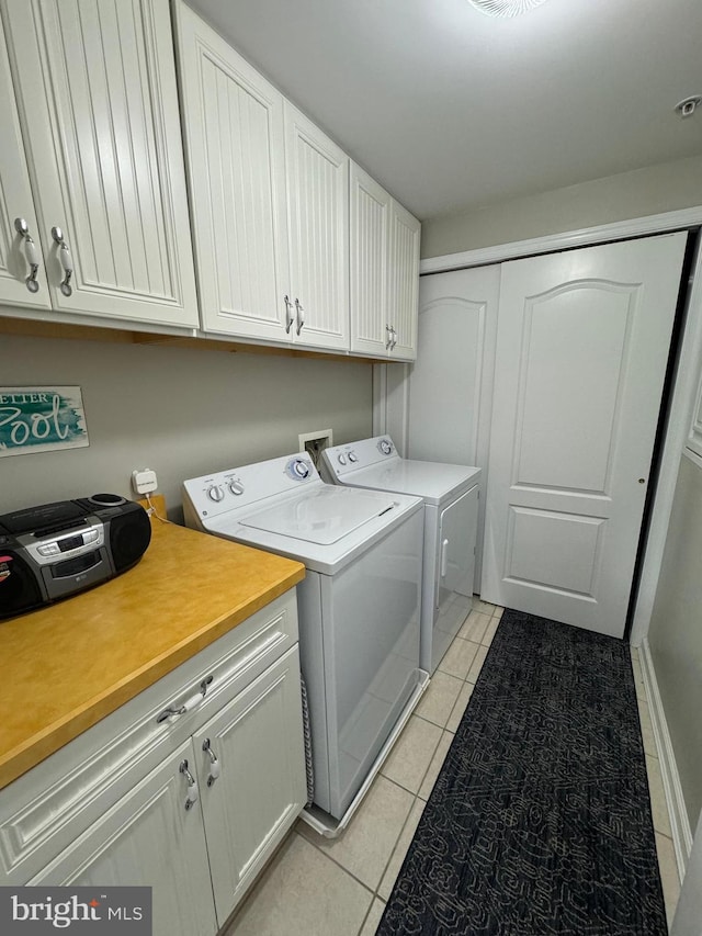 washroom with cabinets, washer and dryer, and light tile patterned floors