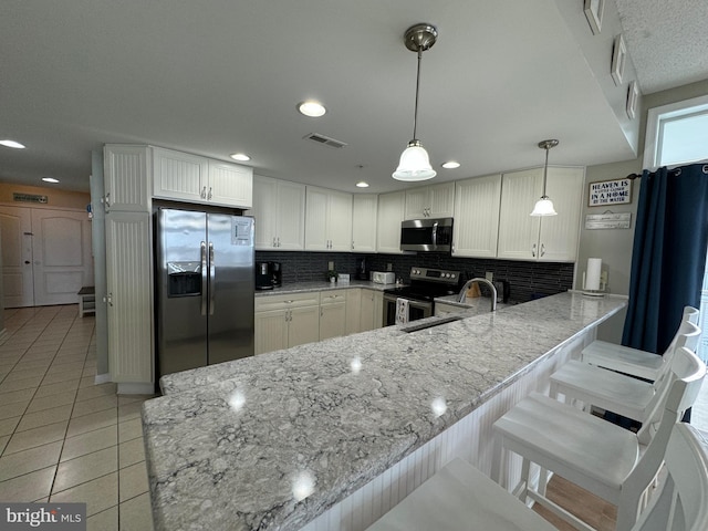 kitchen with stainless steel appliances, hanging light fixtures, white cabinets, and kitchen peninsula