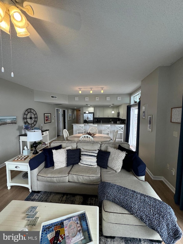 living room featuring hardwood / wood-style flooring, ceiling fan, and a textured ceiling