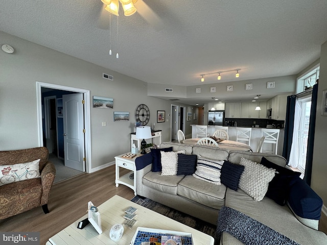 living room with hardwood / wood-style floors, ceiling fan, and a textured ceiling