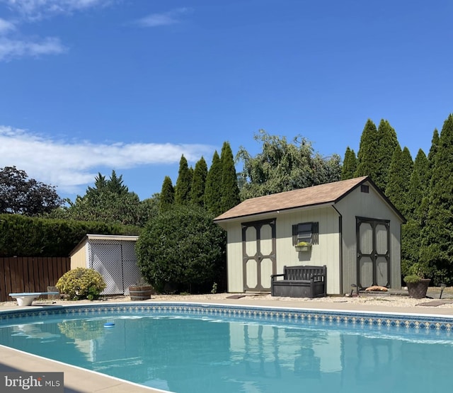 view of pool with a diving board and a storage shed