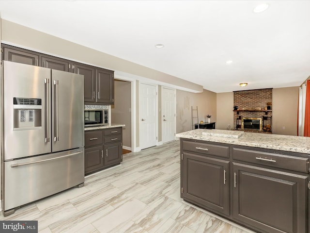 kitchen with a fireplace, light stone countertops, and stainless steel appliances