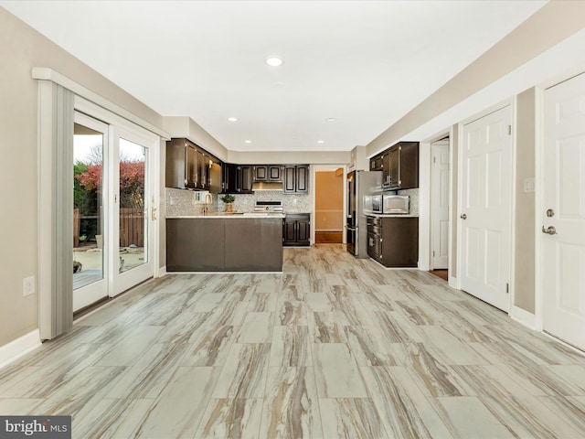 kitchen with sink, stainless steel appliances, tasteful backsplash, kitchen peninsula, and dark brown cabinets