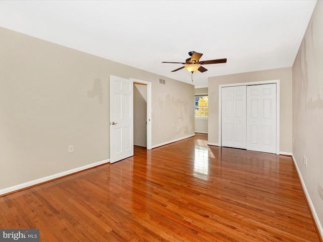 unfurnished bedroom featuring ceiling fan, a closet, and hardwood / wood-style flooring