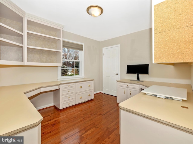 unfurnished office featuring hardwood / wood-style floors and built in desk