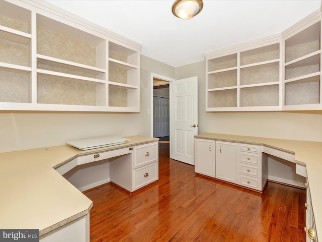 unfurnished office with dark wood-type flooring and built in desk