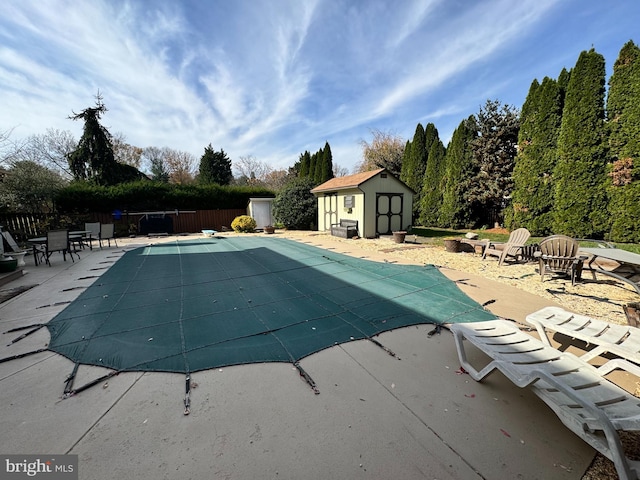 view of pool with a shed and a patio area