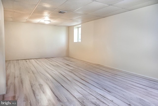 spare room featuring light hardwood / wood-style flooring and a paneled ceiling