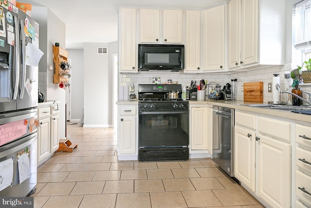 kitchen featuring white cabinetry, sink, black appliances, light tile patterned floors, and decorative backsplash