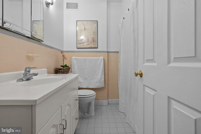 bathroom with tile walls, vanity, tile patterned floors, and toilet