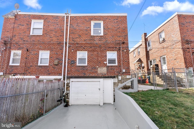 back of property with a garage and a lawn